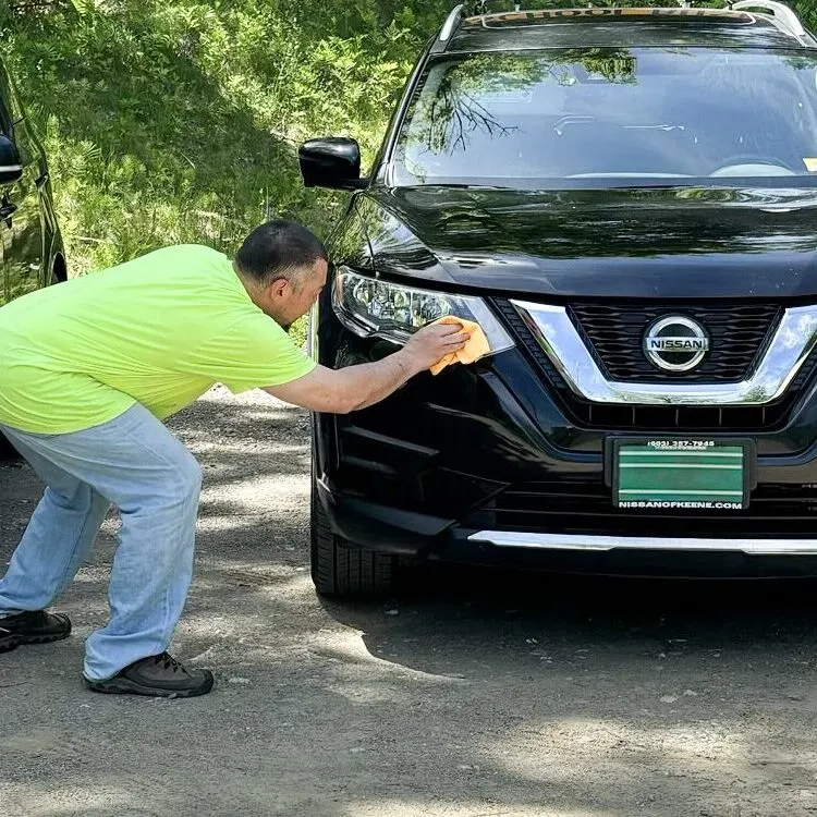 Here to There employee cleaning a car headlight